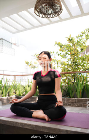 Belle femme faisant du yoga à l'extérieur sur une terrasse sur le toit Banque D'Images