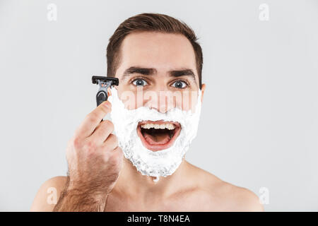 Portrait d'un bel homme barbu avec de la mousse à raser sur son visage isolés sur fond blanc, prêt pour le rasage Banque D'Images