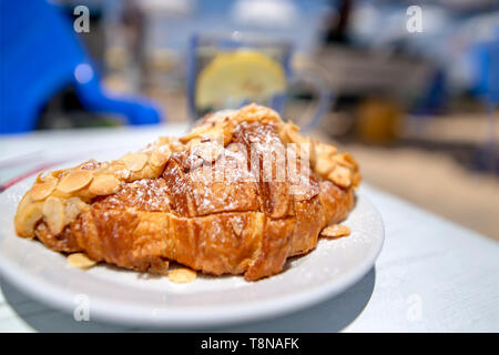 Croisson saupoudrés d'amandes et de sucre en poudre gros plan sur un arrière-plan flou. Banque D'Images