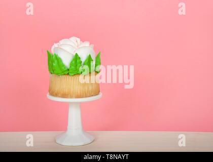 Grande tasse gâteau avec glaçage rose géant assis sur socle blanc sur la table en bois. Design simple avec copie espace pour la Fête des mères, Saint Valentin, Quin Banque D'Images