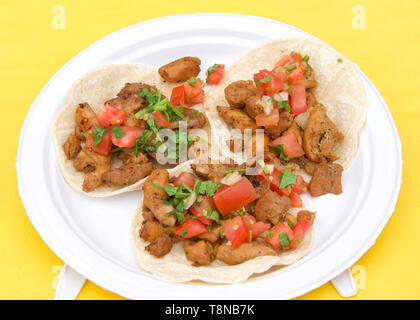 Papier blanc avec plaque de rue poulet tacos sur nappe jaune. Foire de rue populaire de la nourriture. Banque D'Images