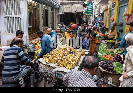 Les hommes sur les motos passer une voiture du vendeur de fruits dans une rue étroite du marché, vieille ville de Varanasi, Inde Banque D'Images