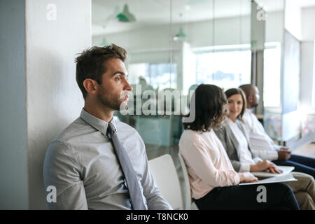 L'homme en attente pour une entrevue d'emploi nerveusement dans un bureau Banque D'Images