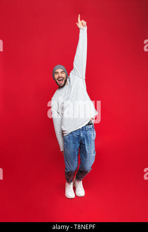 Longueur totale de l'image 30s homme unshaved avec barbe et la moustache de rire en se tenant debout sur fond rouge isolé Banque D'Images