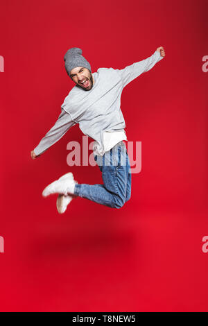 Toute la longueur libre de l'homme 30s avec saut barbe et moustache alors que sur fond rouge isolé Banque D'Images