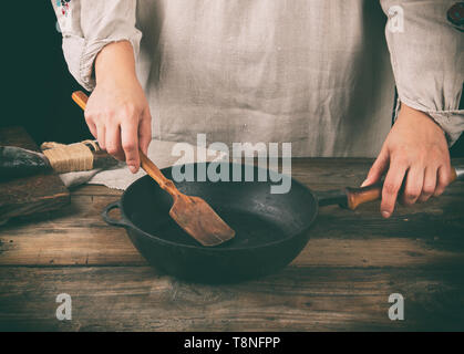 Women's Hands provoquerait une casserole noire et d'une spatule en bois, un tableau gris Banque D'Images