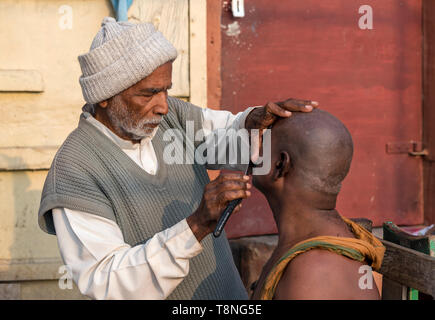 Salon de coiffure de la rue un homme se rase sur les ghats du Gange, Varanasi, Inde Banque D'Images