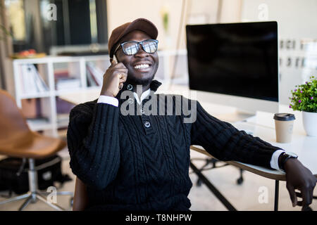 Portrait of male executive making phone call while sitting in office. Young businessman talking on mobile phone. Banque D'Images