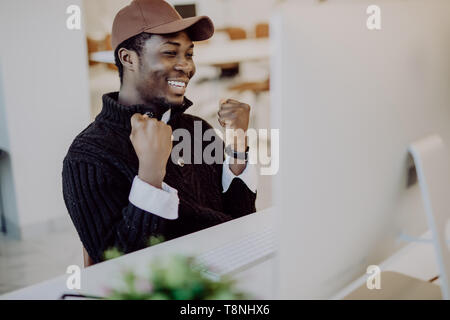 Happy african-american businessman in suit looking at laptop excité par de bonnes nouvelles en ligne, black man sitting at office desk gagnant objectif atteint et aux raisins Banque D'Images