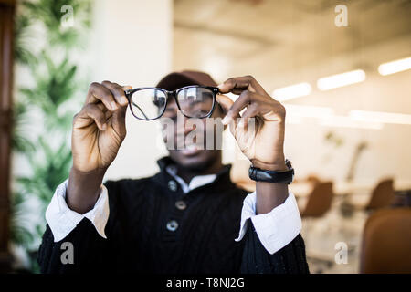 Fatigué de travail a souligné l'ordinateur african american holding eyesglasses devant in modern office Banque D'Images