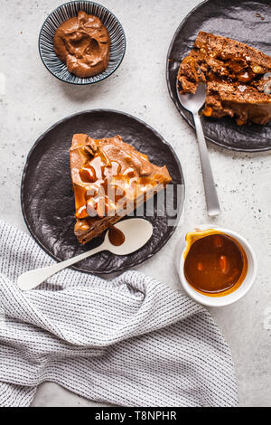 Morceaux de snickers maison gâteau au chocolat et caramel crème noire sur une soucoupe, fond blanc, vue du dessus. Banque D'Images