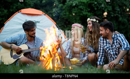 Groupe d'amis camping.Ils sont assis autour d'un feu de camp, jouer de la guitare Banque D'Images