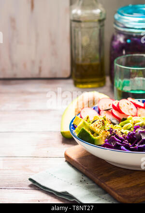 Bol Bouddha avec des couleurs arc-en-ciel - avocat ingrédients fermentés, du chou rouge, quinoa, radis, haricots verts, le sésame et les graines de citrouille. Servie sur wo Banque D'Images
