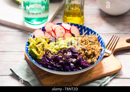 Bol Bouddha avec des couleurs arc-en-ciel - avocat ingrédients fermentés, du chou rouge, quinoa, radis, haricots verts, le sésame et les graines de citrouille. Servie sur wo Banque D'Images