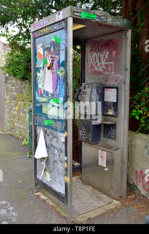 Téléphone britannique moderne fort vandalisé avec des affiches, marquage et graffiti Banque D'Images