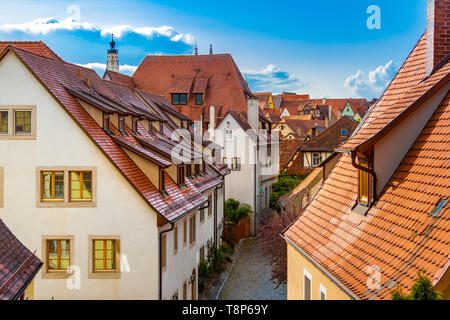 Vue sur le toit pittoresque typique d'une voie dans la ville médiévale de Rothenburg ob der Tauber avec ses maisons de bois colorés, un ciel bleu et la pointe... Banque D'Images