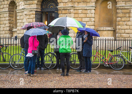 Une fête de touristes avec des parasols colorés dans la pluie à Radcliffe Square, Oxford par la caméra Radcliffe Banque D'Images