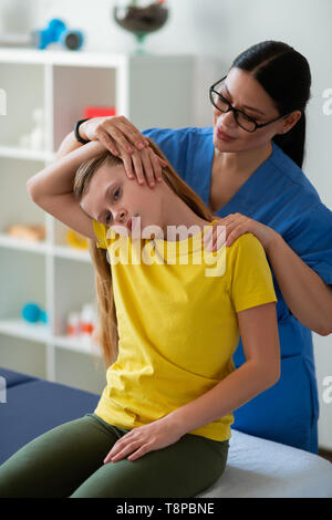 Bon sourire à l'appui de l'infirmière petite fille au cours des exercices spéciaux Banque D'Images