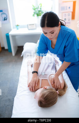 Dark-haired woman talentueux faisant précisément back massage Banque D'Images