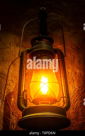 Une vieille lampe d'argile se bloque sur un mur dans une pièce sombre. Banque D'Images