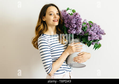 Belles femmes avec un bouquet de lilas mauve sur fond blanc Banque D'Images