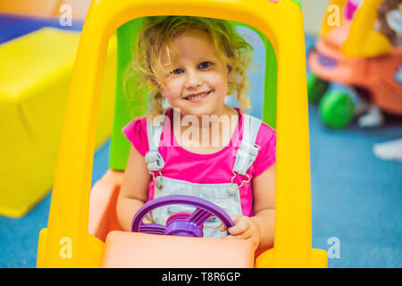 Petite fille conduit une voiture colorée jouet Banque D'Images