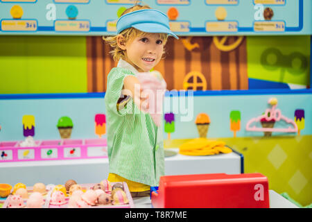 Un garçon joue dans une cuisine, fait un jouet ice cream Banque D'Images