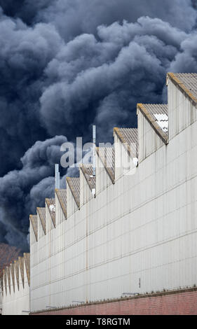 Des panaches de fumée d'un incendie industriels toxiques dans une usine derrière un bâtiment. Banque D'Images