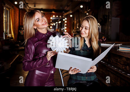 Salon de beauté, cheveux Colorant et personnes concept. Smiling blonde jeune femme et coiffure choisir la couleur de cheveux de coloration de cheveux dans la palette avant de salo Banque D'Images