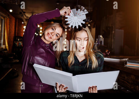 Salon de beauté, cheveux Colorant et personnes concept. Smiling blonde jeune femme et coiffure choisir la couleur de cheveux de coloration de cheveux dans la palette avant de salo Banque D'Images