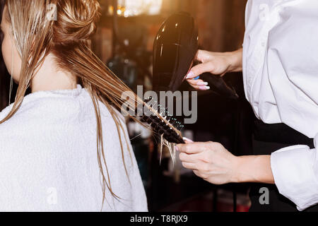 Coiffure cheveux homme blond de séchage avec un sèche-cheveux professionnel dans un salon de beauté. Libre de coiffeur à l'aide de brosse et d'un sèche-cheveux. Banque D'Images