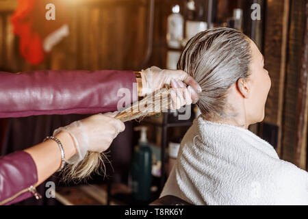 Coiffure cheveux tirant du client après l'application du masque. Cheveux forts et sains. Spa, soins capillaires, argile cheveux concept. Banque D'Images