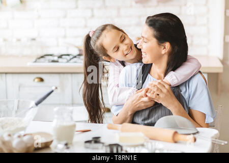 Loving daughter hugging sa mère dans la cuisine. Banque D'Images
