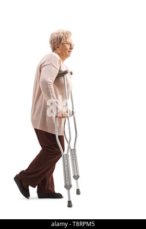 Profil de pleine longueur de balle a senior woman marcher avec des béquilles isolé sur fond blanc Banque D'Images