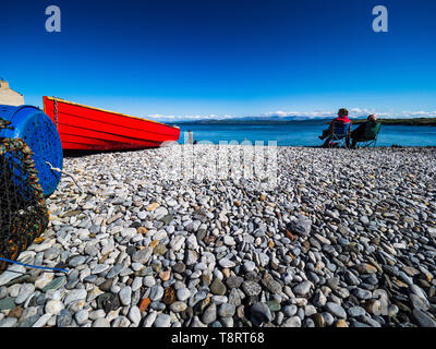 Affilmomo - British Beach Holidays - Anglesey - plage de galets avec bateau rouge Banque D'Images