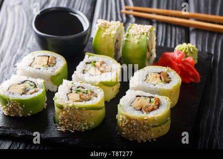 Rouleau japonais vert avec de l'avocat, tamago omelette, sésame et gros plan de concombre sur une plaque sur la table horizontale. Banque D'Images