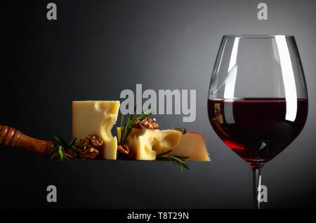 Fromage Maasdam aux noix, le romarin et le vin rouge sur un fond sombre. Copier l'espace. Banque D'Images