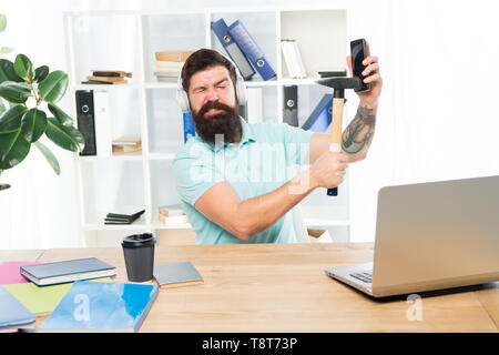 Travail stressant au centre d'appel. Homme barbu bureau casque hammer smartphone. L'embarras de la communication. Mobile n négociations. Le plus ennuyeux sur un travail en centre d'appel. Appel entrant. Banque D'Images