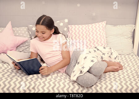 Histoire fascinante. Petite fille lay lit avec oreillers lire livre. Kid se préparer à aller au lit. Temps pour soir histoire fascinante. Kid fille cheveux longs pyjamas mignons vous détendre et lire la fascinante histoire d'adresses. Banque D'Images