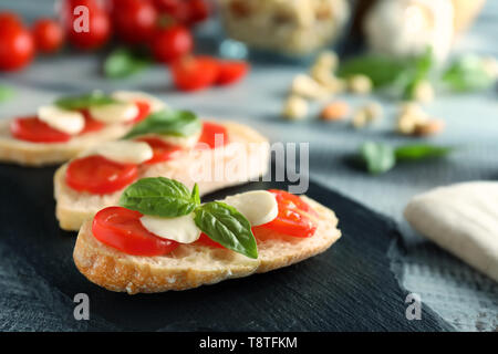 Pain frais avec des tomates, fromage mozzarella et basilic vert sur la plaque d'ardoise Banque D'Images