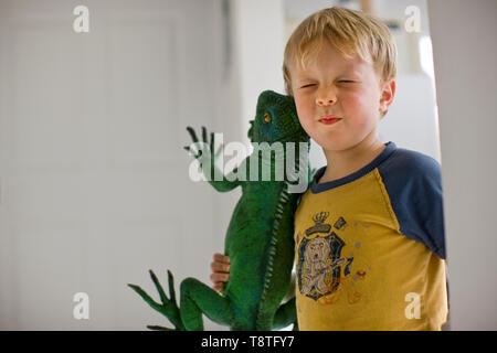 Un jeune garçon tenant un grand lézard de jouets. Banque D'Images