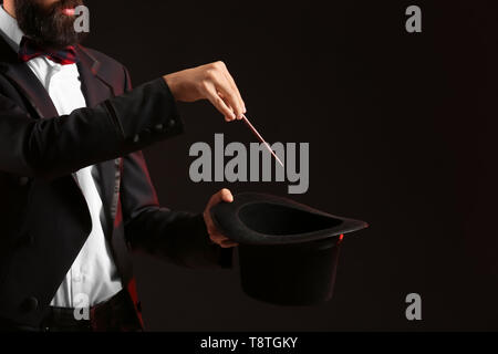Magicien montrant des tours sur fond sombre Banque D'Images