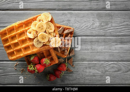 De délicieuses gaufres aux bananes, fruits rouges et de chocolat sur fond de bois, vue du dessus Banque D'Images