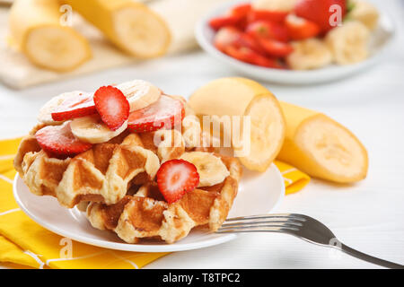 De délicieuses gaufres aux fraises et des tranches de banane sur la plaque Banque D'Images