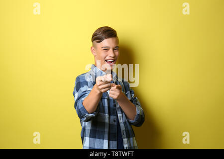 Smiling teenage boy pointing at viewer sur un fond de couleur Banque D'Images