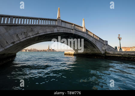 Pont de pierre traversant l'un des nombreux canaux de la ville, le Grand Canal et di San Giorgio Maggiore dans la distance Banque D'Images