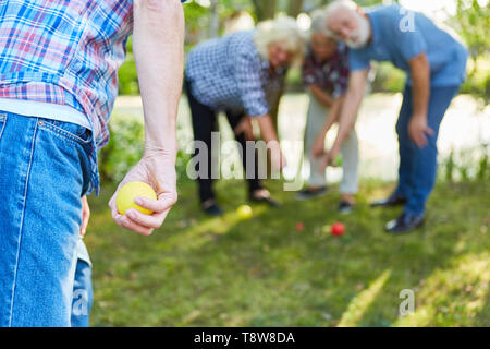 L'homme est le but avec la balle à la pétanque et au jeu de boules dans le jardin avec des amis Banque D'Images