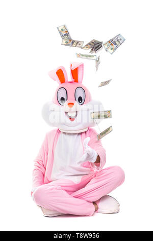 Lapin de Pâques lance de dollars, célèbre Pâques. Lucky Man riche personne sous la pluie de centaines de dollar bills Banque D'Images