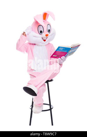 Drôle de lapin de pâques lit le livre, reçoit une éducation, d'essayer d'être intelligent. Taille de la vie avec costume de lapin livre sur fond blanc Banque D'Images