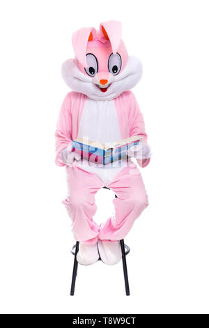 Taille de la vie avec costume de lapin livre sur fond blanc. Lapin de Pâques lit le livre, reçoit une éducation, essayant d'être intelligent Banque D'Images